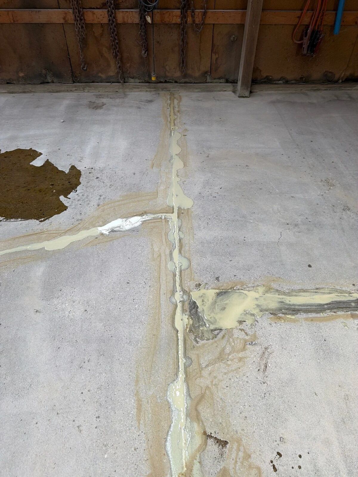 Concrete garage slab with cracks cut open and filled with repair material before coating