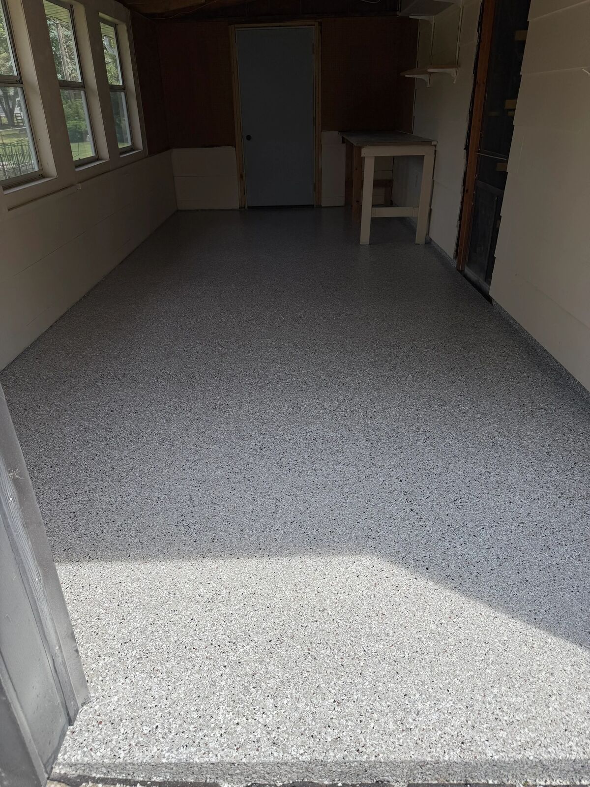 Finished flake floor in a narrow garage with a bench and windows